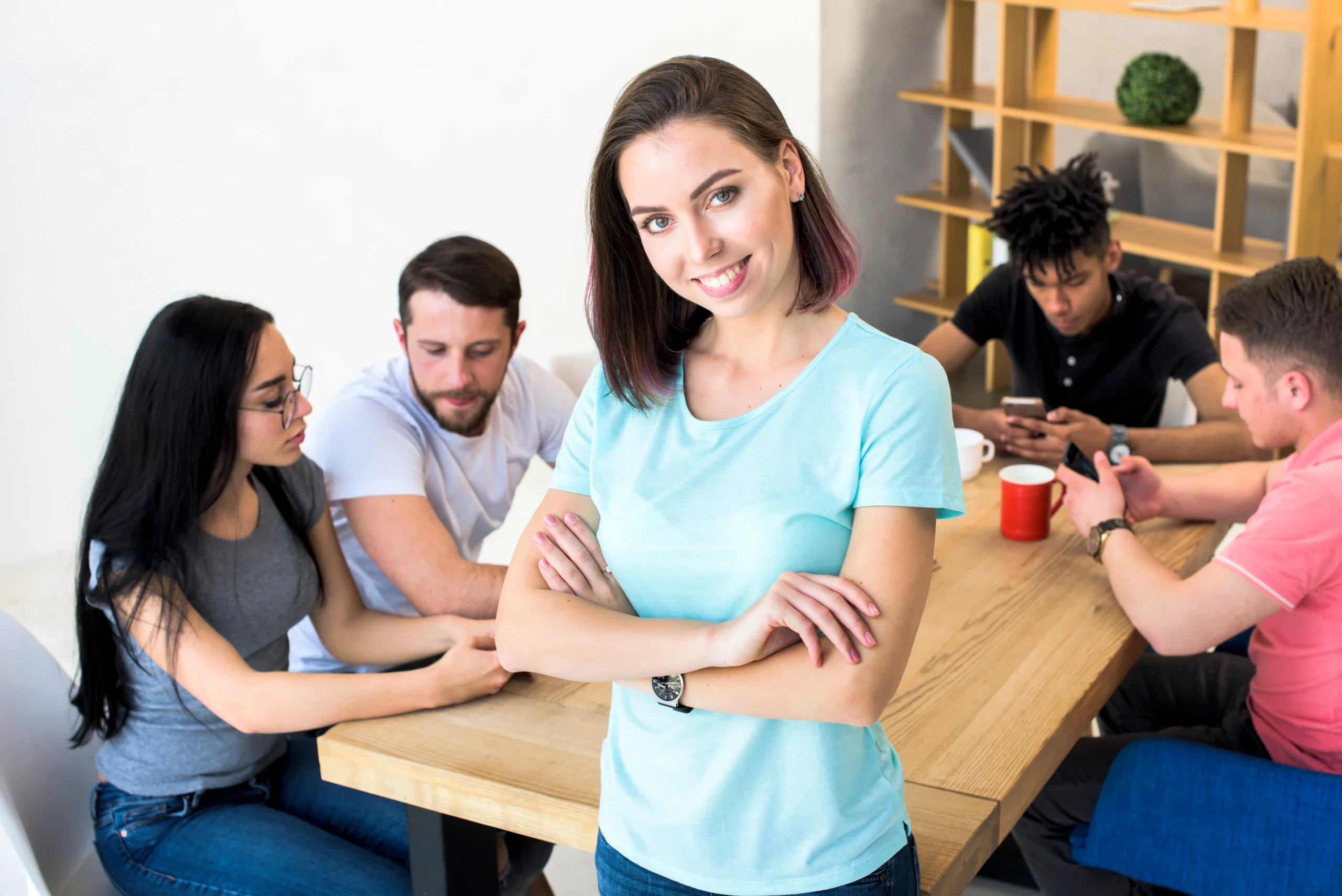portrait pretty woman with arm crossed standing with her friends sitting